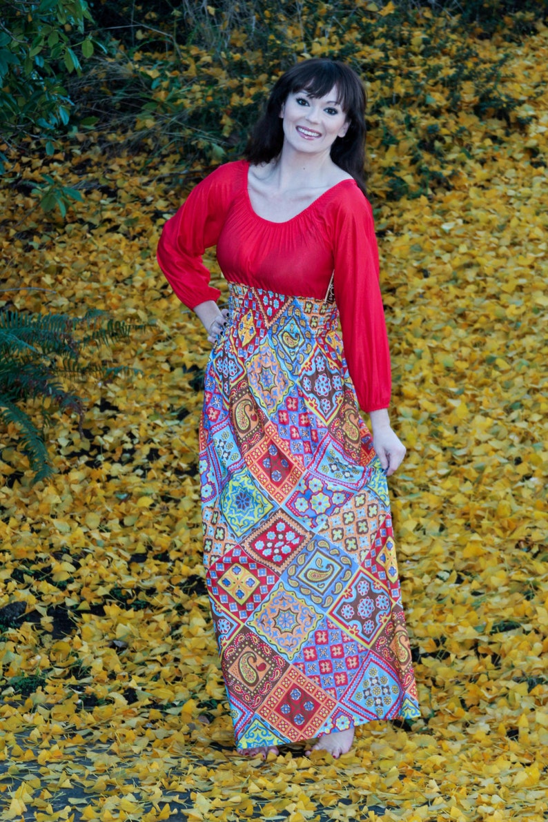 K&ouml;nnte beinhalten: Eine Frau tr&auml;gt ein rot-wei&szlig;es Maxikleid mit einem roten Oberteil und einem langen Rock. Sie steht auf einem Feld mit gelben Bl&auml;ttern.