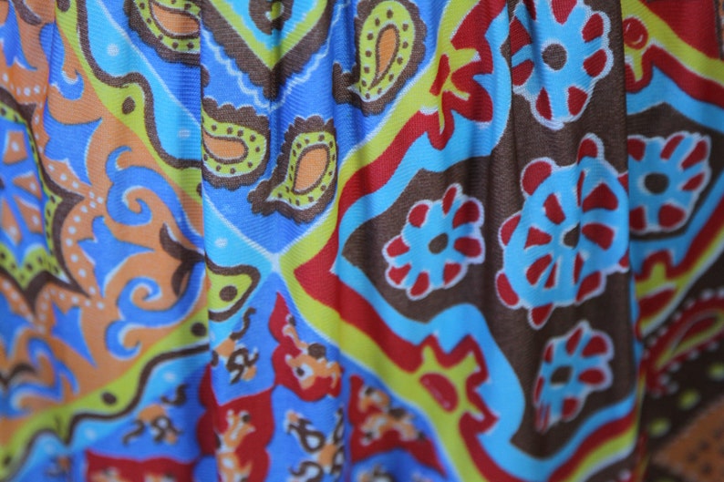 K&ouml;nnte beinhalten: Nahaufnahme eines bunten Stoffes mit Paisley-Muster. Der Stoff ist blau, rot, gr&uuml;n, gelb und braun. Das Muster ist kompliziert und detailliert.
