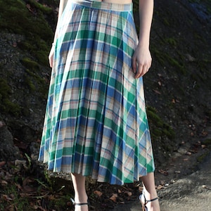 May include: A pleated midi skirt with a plaid pattern in shades of blue, green, white, and red.