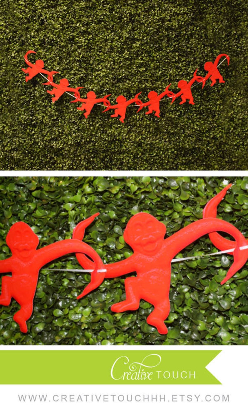 K&ouml;nnte beinhalten: Rote Papier-Affen-Ausschnitte, die zu einer Girlande zusammengef&uuml;gt sind. Die Girlande h&auml;ngt vor einem gr&uuml;nen Hintergrund. Der Text "Creative Touch" und eine Website-Adresse sind unten im Bild sichtbar.