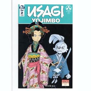 May include: Comic book cover for Usagi Yojimbo #2, featuring a geisha and a samurai rabbit. The geisha wears a pink kimono with floral patterns. The rabbit samurai is in a blue kimono and holds a sword. The title is in white letters.