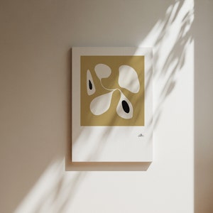 Op de afbeelding: Abstracte kunstprint met een wit en zwart ontwerp op een mosterdgele achtergrond.