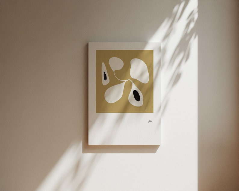 Op de afbeelding: Abstracte kunstprint met een wit en zwart ontwerp op een mosterdgele achtergrond.