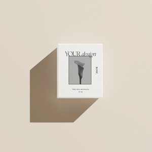 Pu&ograve; includere: Un mockup di scatola bianca con una foto in bianco e nero di un fiore sul davanti. Il testo "YOUR design ROW." &egrave; stampato sulla scatola. La scatola &egrave; su uno sfondo beige chiaro.