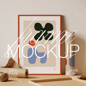 May include: A framed abstract art print with a red, blue, and green color scheme. The frame is a light orange color. The print is titled "Dina Frame Ratio" and is made by Row.