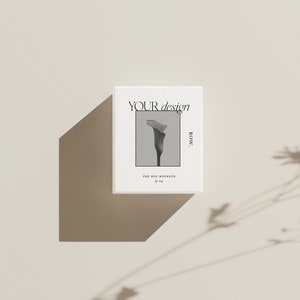 Pu&ograve; includere: Scatola quadrata bianca con una foto in bianco e nero di un fiore sul davanti. Il testo "YOUR design ROW." &egrave; stampato sulla scatola.