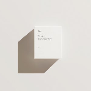 Pu&ograve; includere: Mockup di scatola bianca con il testo "Box Mockup Your image here PSD" sul davanti.