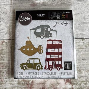 May include: Sizzix Thinlits die set with a camper, submarine, double-decker bus, car, and the letter "T". The package includes the text "4 DIES 4 MATRICES 4 TROQUELES 4 FUSTELLE 4 BЫPУБKИ 4 STANZEN 4 CORTANTES".