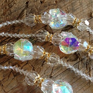 May include: A strand of iridescent crystal beads with gold accents. The beads are faceted and have a rainbow effect.