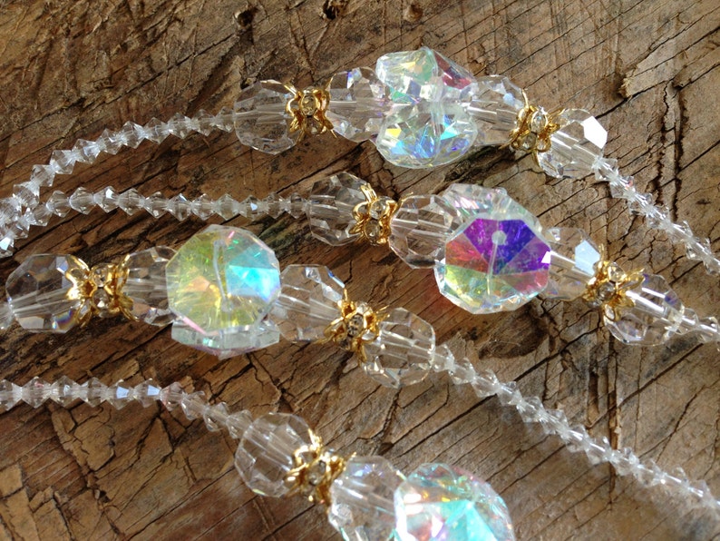 May include: A strand of iridescent crystal beads with gold accents. The beads are faceted and have a rainbow effect.