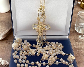 May include: A gold and crystal rosary with a large crystal cross in a blue velvet box. The rosary beads are made of small, faceted crystals in a light beige color.