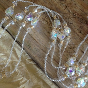 May include: A multi-strand crystal necklace with gold accents. The necklace features clear faceted crystals and small gold beads.