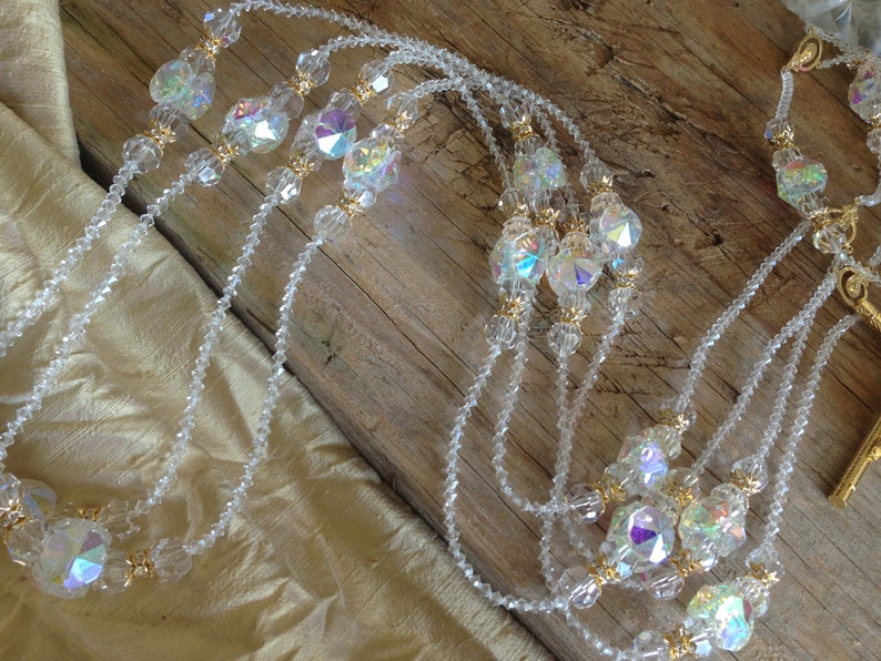 May include: A multi-strand crystal necklace with gold accents. The necklace features clear faceted crystals and small gold beads.