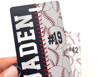 May include: A personalized baseball-themed tag with the name "JADEN" in white block letters on a navy blue background. The right side features a baseball pattern with the number "19". A second tag with the number "42" is visible.