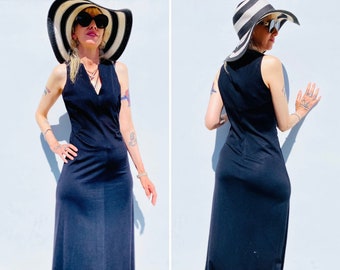 Può includere: Un abito maxi nero senza maniche con scollo a V. La modella indossa un cappello a tesa larga a righe bianche e nere e occhiali da sole.