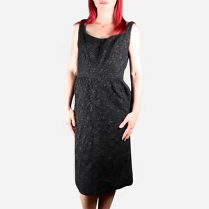 Puede incluir: Un vestido negro sin mangas con un estampado floral. El vestido tiene un escote redondo y un corpiño ajustado. La falda es ligeramente acampanada.