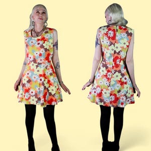 以下が含まれることがあります： カラフルな花柄のプリントが施されたノースリーブのミニドレス。ドレスはフィットしたボディとフレアスカートになっています。ドレスは軽量な生地で作られており、夏に最適です。
