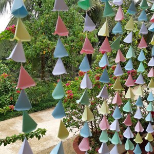 Peut inclure: Une guirlande de triangles en papier de couleur suspendue à un plafond. Les triangles sont dans des tons de rose, bleu, vert et jaune.