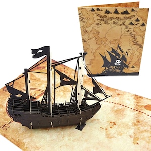 May include: A black 3D pop-up card featuring a pirate ship sailing on a treasure map. The card is open and the ship is fully extended. The map is a vintage style with brown and tan colors.