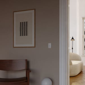 May include: A light brown wooden chair with a curved back and a white globe lamp on a stack of books in a room with a light brown wall and a doorway leading to another room.