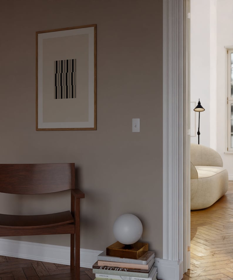 May include: A light brown wooden chair with a curved back and a white globe lamp on a stack of books in a room with a light brown wall and a doorway leading to another room.