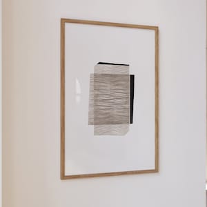 May include: A framed abstract art print with a white background and a layered design of textured paper in shades of gray and black.