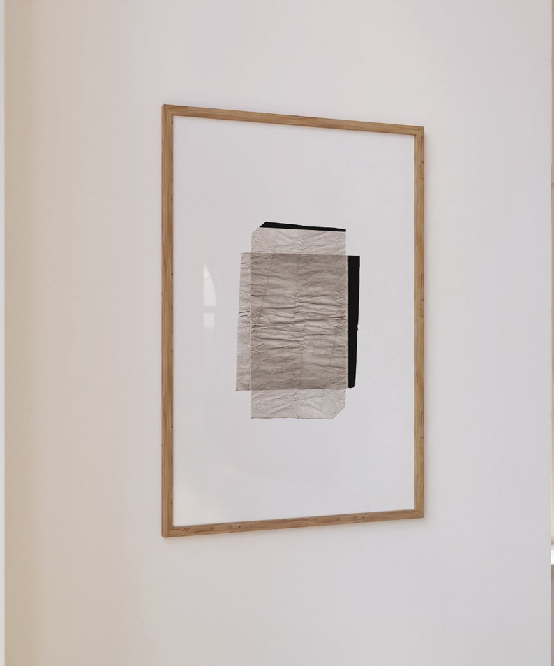 May include: A framed abstract art print with a white background and a layered design of textured paper in shades of gray and black.