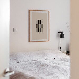 May include: A white bed with a white linen duvet cover and a framed print of a geometric design on the wall above the bed.
