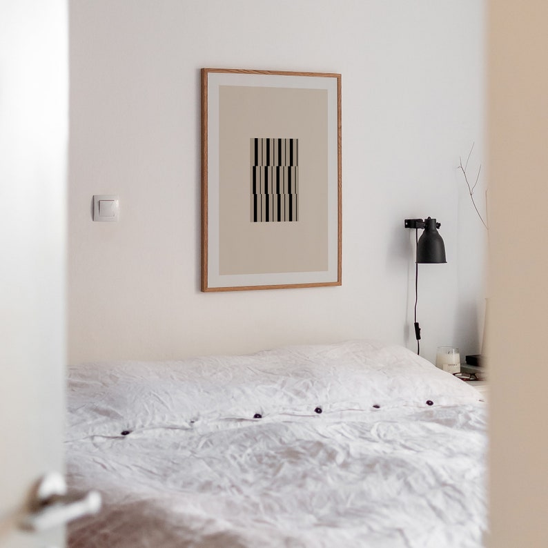 May include: A white bed with a white linen duvet cover and a framed print of a geometric design on the wall above the bed.