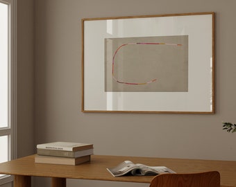 May include: A framed abstract art print with a colorful line drawing of a curved shape on a beige background. The frame is made of natural wood and has a white mat. The print is hanging on a light brown wall above a wooden desk with books and a magazine.