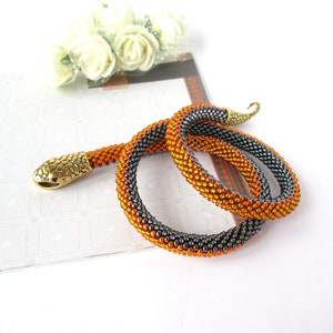 May include: A beaded snake necklace with a gold snake head and orange and gray beads.