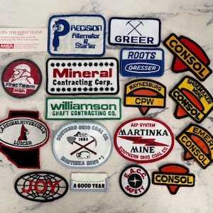 May include: A collection of various embroidered fabric patches featuring company logos and text including Precision Alternator & Starter, Mineral Contracting Corp, Williamson Shaft Contracting Co, Consol, Martinka Mine, and First Team MSA.