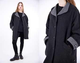 May include: A long, dark gray coat with a gray collar and cuffs. The coat has a button closure and two pockets.