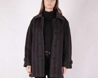 May include: A dark gray wool coat with a collar and button closure. The coat has a slightly oversized fit and a textured fabric.