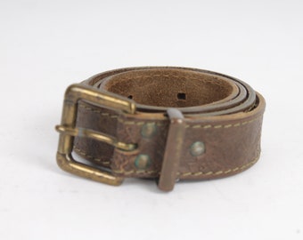 May include: A brown leather belt with a brass buckle. The belt has a decorative pattern and stitching.