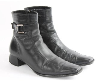 May include: A pair of black leather ankle boots with a buckle strap and a square toe.