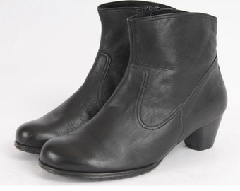 May include: Black leather ankle boots with a low block heel. The boots have a zipper on the inside of the ankle and a pointed toe.