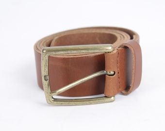 May include: A brown leather belt with a gold-toned buckle. The belt is rolled up and the buckle is closed.