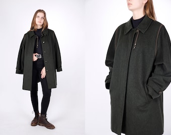May include: A dark green wool coat with brown leather trim and a long, pointed collar. The coat has a button closure and two pockets.