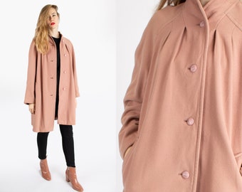 May include: A long, blush pink coat with a stand-up collar and button closure. The coat has a relaxed fit and features pleats on the back.