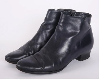 May include: A pair of dark blue leather ankle boots with a low heel. The boots have a zipper on the inside of each ankle.