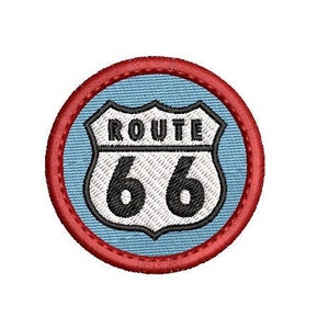 May include: An embroidered patch featuring a white shield with the words "ROUTE 66" in black text, surrounded by a red border and a blue background.