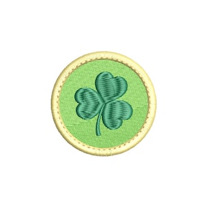 May include: A green shamrock embroidered on a light green circle with a gold outline.