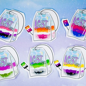 Könnte beinhalten: Sechs bunte Teebeutel-Etiketten mit dem aufgedruckten Text "LGBTea". Jedes Etikett zeigt ein anderes Farbschema der Pride-Flagge, darunter die bisexuelle, transgender, lesbische, pansexuelle, genderqueer und asexuelle Flagge.