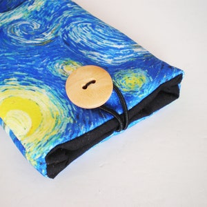 May include: A blue and yellow fabric pouch with a wooden button closure. The fabric features a swirling pattern reminiscent of Van Gogh's Starry Night.