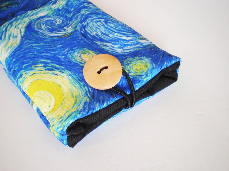 May include: A blue and yellow fabric pouch with a wooden button closure. The fabric features a swirling pattern reminiscent of Van Gogh's Starry Night.