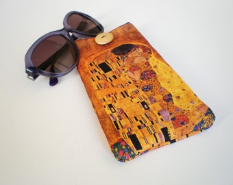 May include: A yellow, brown, and blue fabric eyeglasses case with a print of Gustav Klimt's The Kiss painting. The case has a button closure.