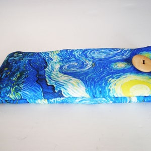 May include: A blue and yellow fabric eyeglass case with a wooden button closure. The case features a print of Vincent van Gogh's "Starry Night" painting.