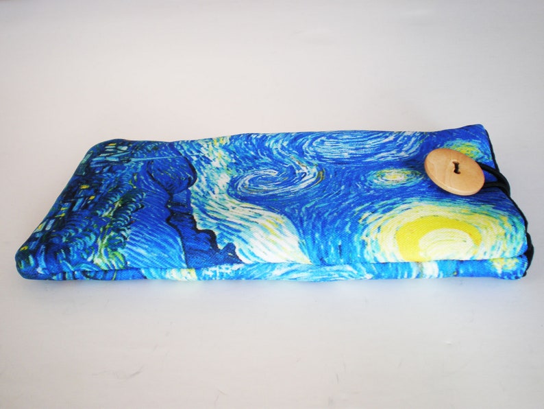 May include: A blue and yellow fabric eyeglass case with a wooden button closure. The case features a print of Vincent van Gogh's "Starry Night" painting.
