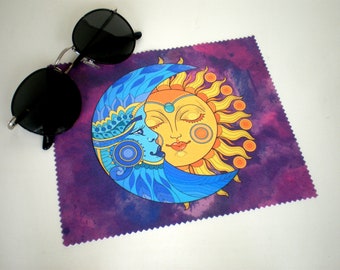 May include: A purple microfiber cleaning cloth with a colorful illustration of a sun and moon with faces. The sun is yellow with orange rays and the moon is blue with intricate details.